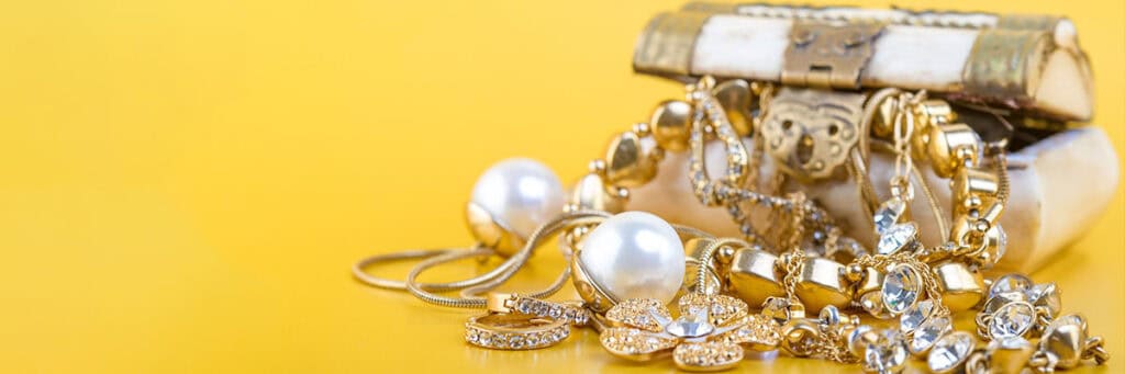 Golden jewelry collection featuring pearls, diamonds, and intricate designs, showcased on a vibrant yellow background emphasizing luxury and elegance.