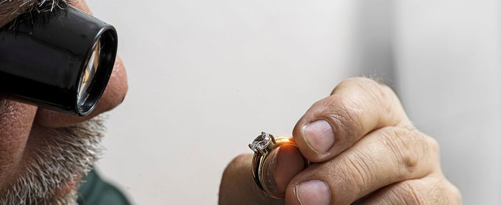 Engagement ring inspection at david stern jewelers with magnifying glass for quality assurance.