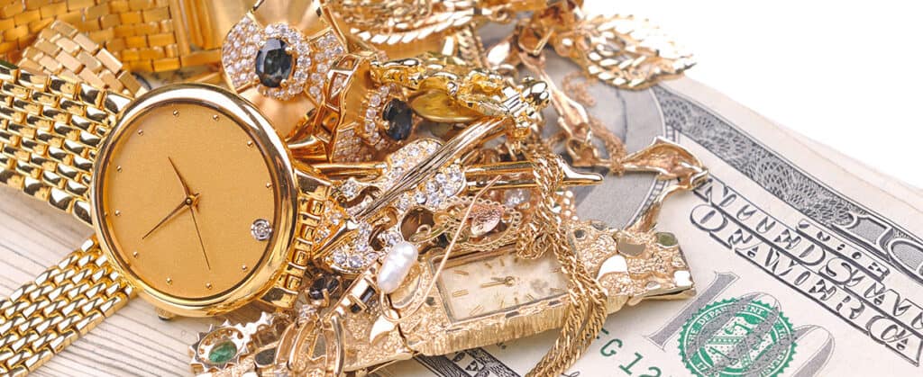 Shiny gold and diamond jewelry including watches, rings, and necklaces piled on cash, showcasing luxury jewelry collections at david stern jewelers.
