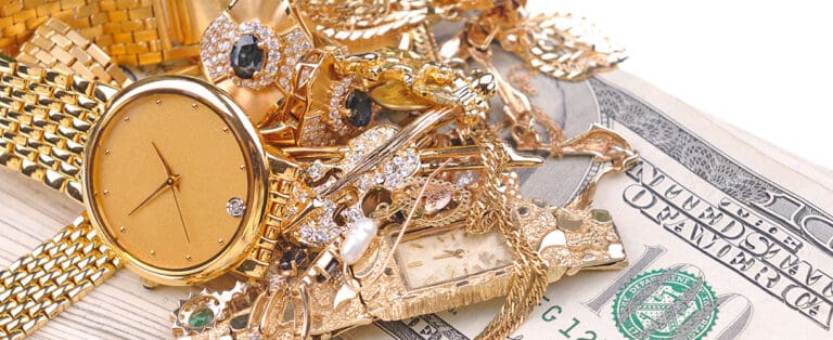 Shiny gold and diamond jewelry including watches, rings, and necklaces piled on cash, showcasing luxury jewelry collections at David Stern Jewelers.