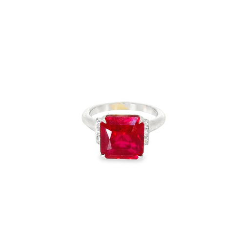 Lab grown ruby solitaire ring seen head on: an emerald cut lab-grown ruby flanked by diamond-set shoulders in 14kt white gold