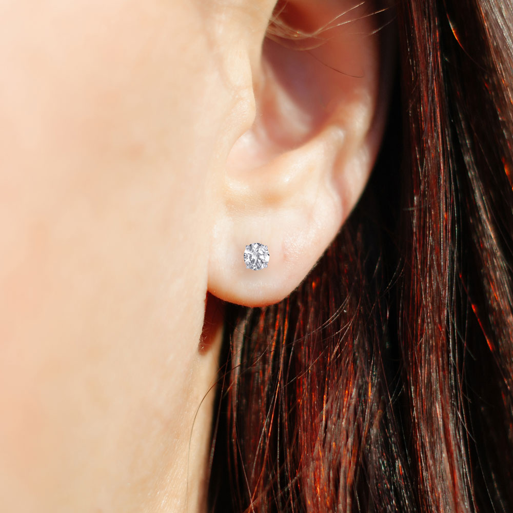 One of the 4 ctw diamond earrings worn on the ear, showing the size of a 2.00 ct round stud