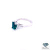 Lab created emerald engagement ring in platinum seen from the left, showing the emerald cut center and baguette side stone