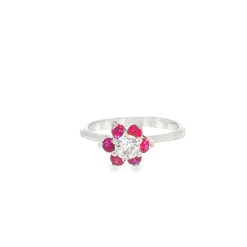 Ruby flower ring in 14kt white gold, viewed from the front: a round diamond center ringed by six round rubies on a slim band