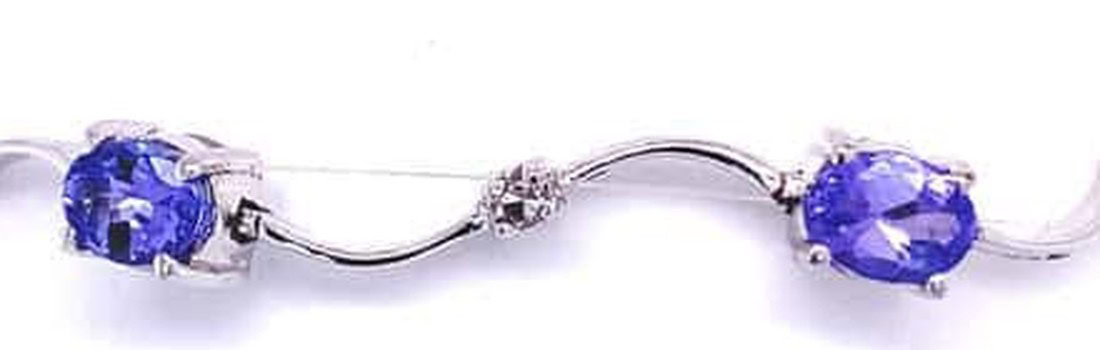 Tanzanite and diamond bracelet detail: prong-set oval tanzanites joined by wavy white gold links with a small diamond at the center