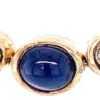 Sapphire station necklace detail: bezel-set oval cabochon sapphire between bezel-set diamonds and grooved gold beads