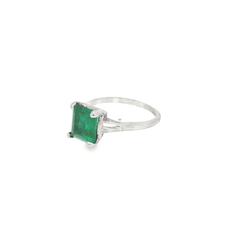 Side view of the emerald cut emerald ring showing the four corner prongs, the tapered baguettes and the slim platinum band
