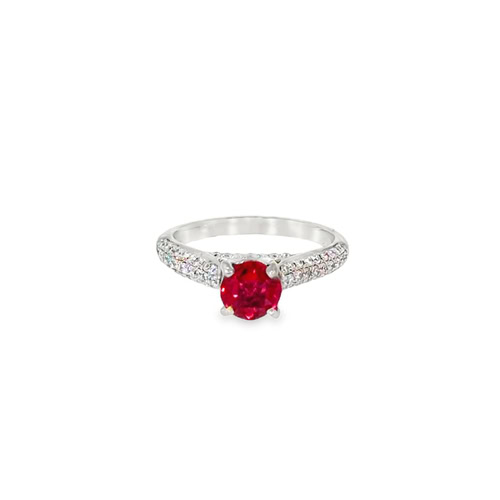 Lab grown ruby ring seen head on: a round red lab-grown ruby held in four prongs above pave diamond shoulders in 14kt white gold