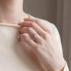 The rose gold halo engagement ring worn on the hand, its round diamond and halo raised above a slim 14kt rose gold band